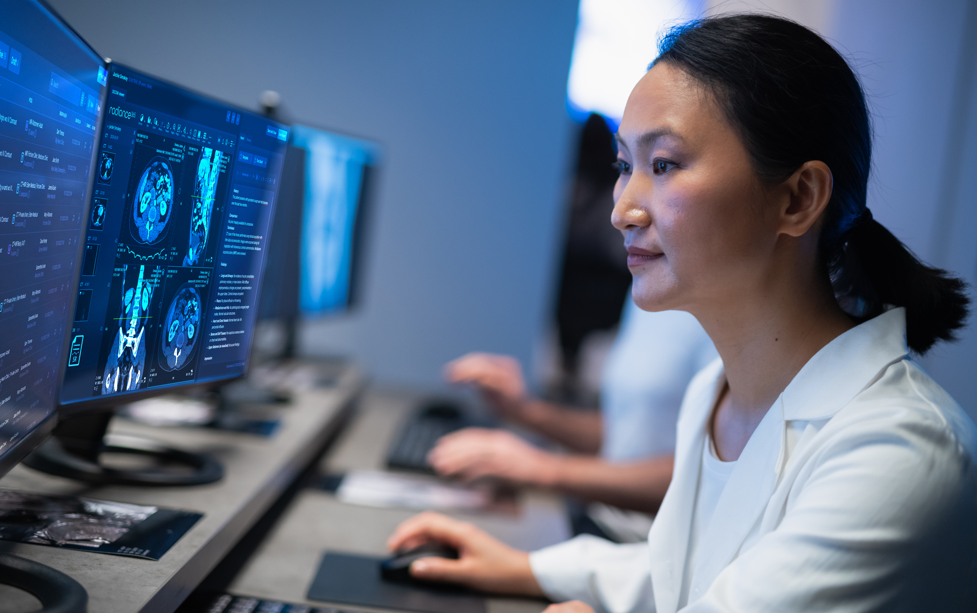 Female radiologist in white coat examining brain scan images on computer monitor in medical imaging workstation